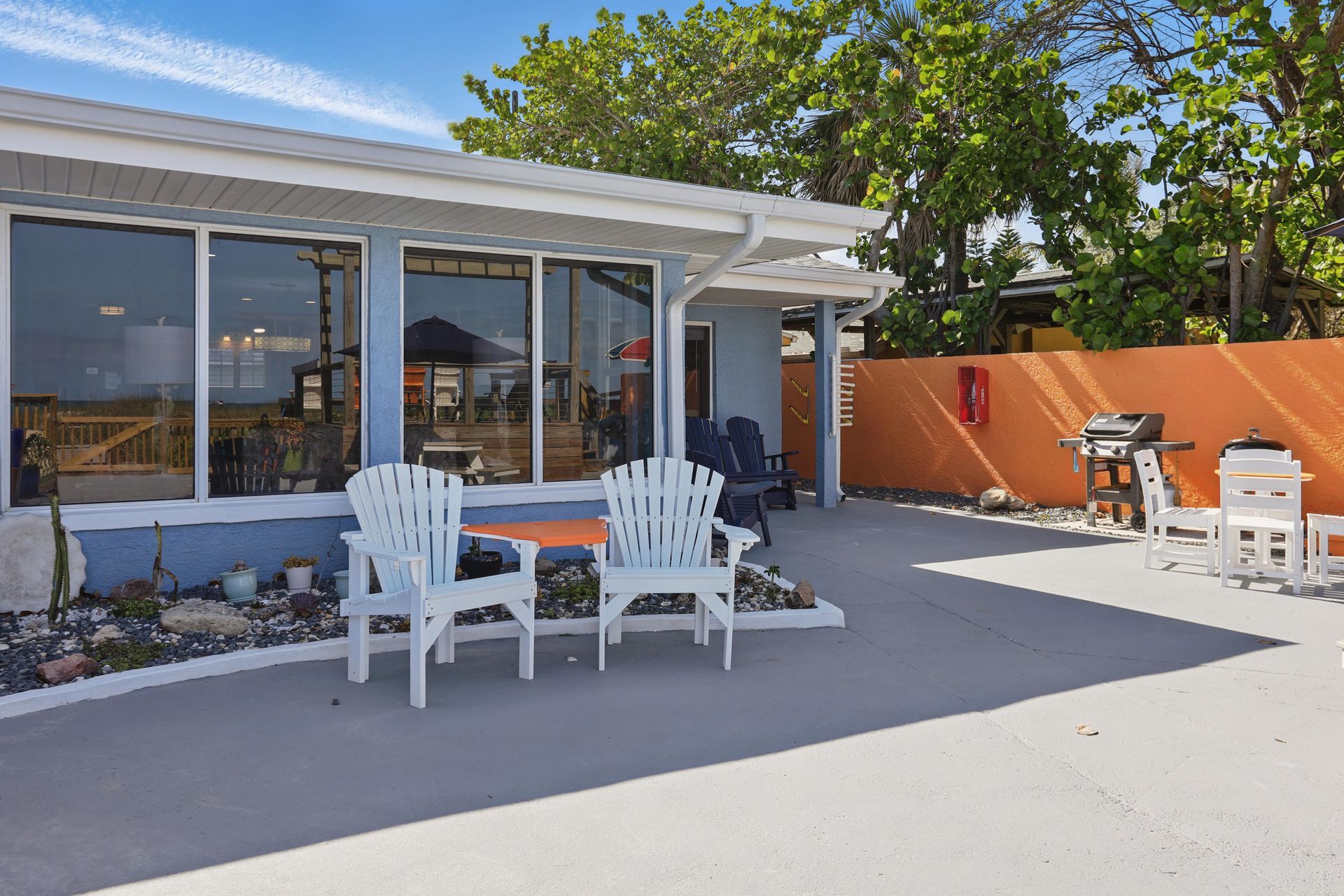 A patio with chairs and a table in front of a house.