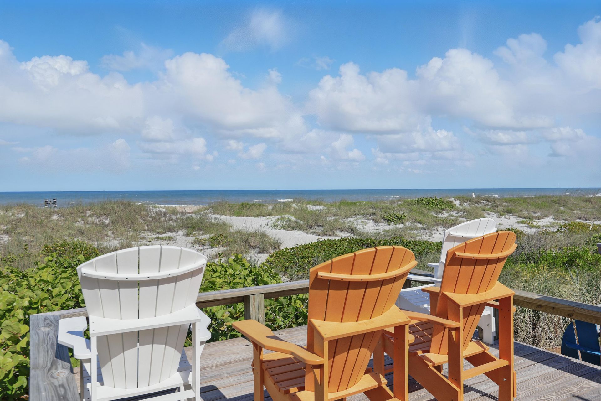 A couple of chairs sitting on top of a wooden deck overlooking the ocean.