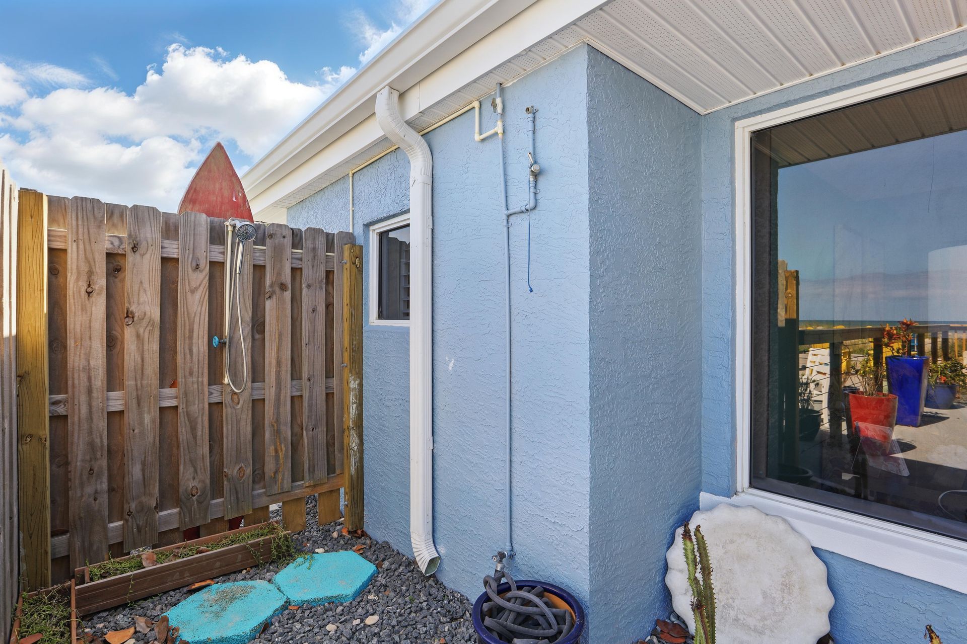 A blue house with a wooden fence and a window.