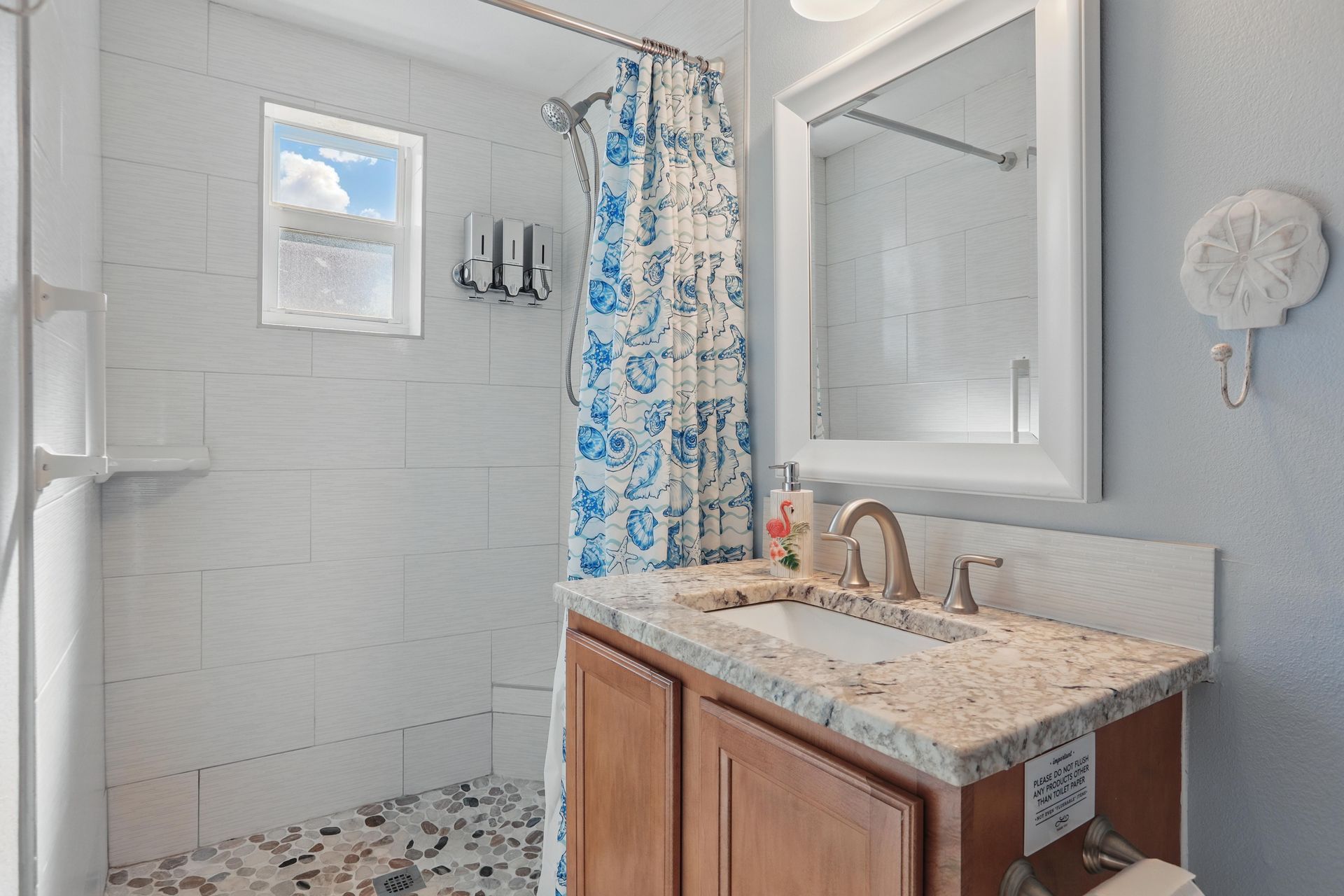 A bathroom with a sink , mirror and shower.