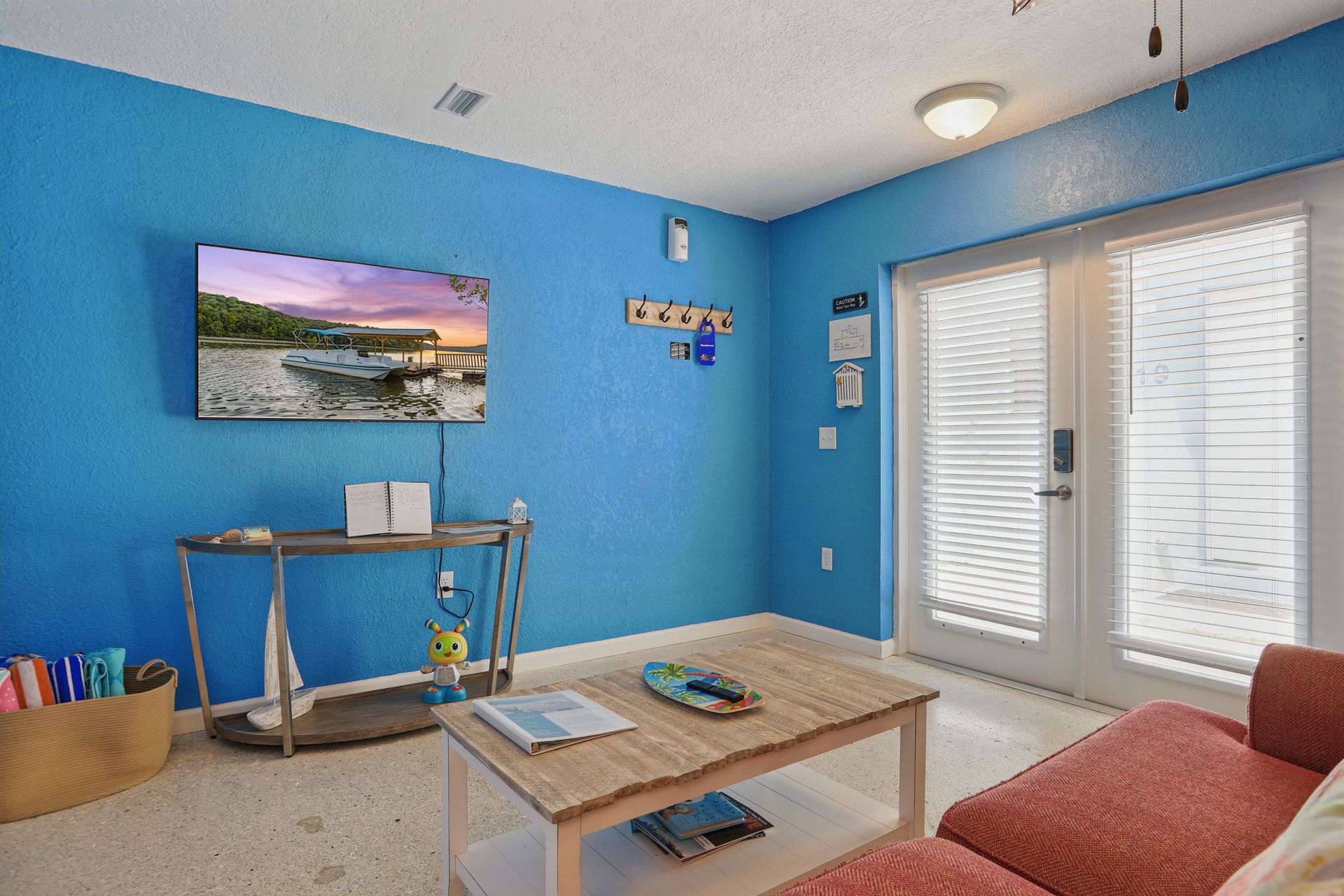 A living room with blue walls , a couch , a coffee table and a flat screen tv.