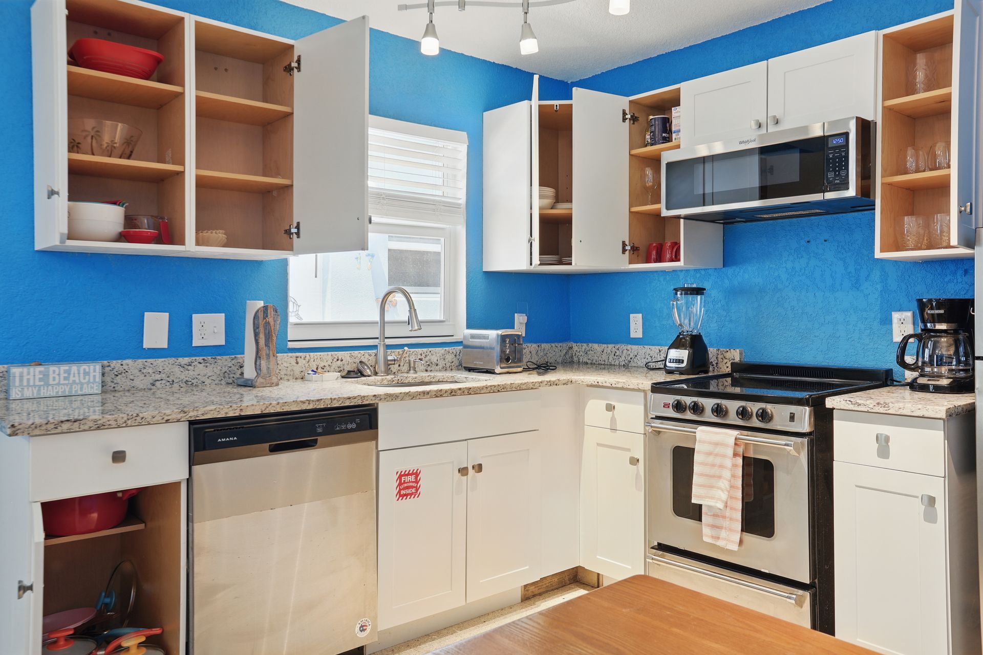 A kitchen with blue walls and white cabinets