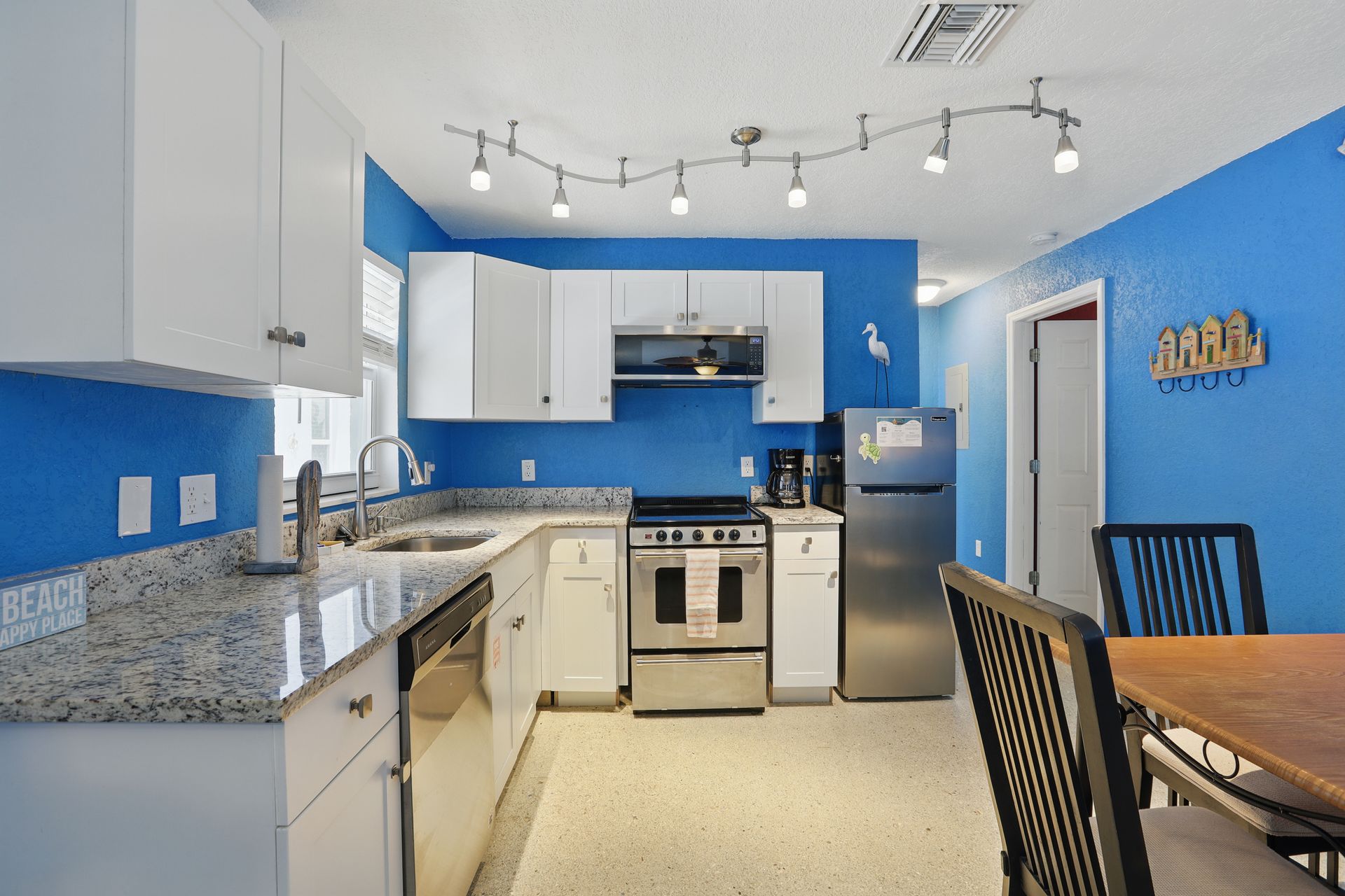 A kitchen with blue walls and white cabinets