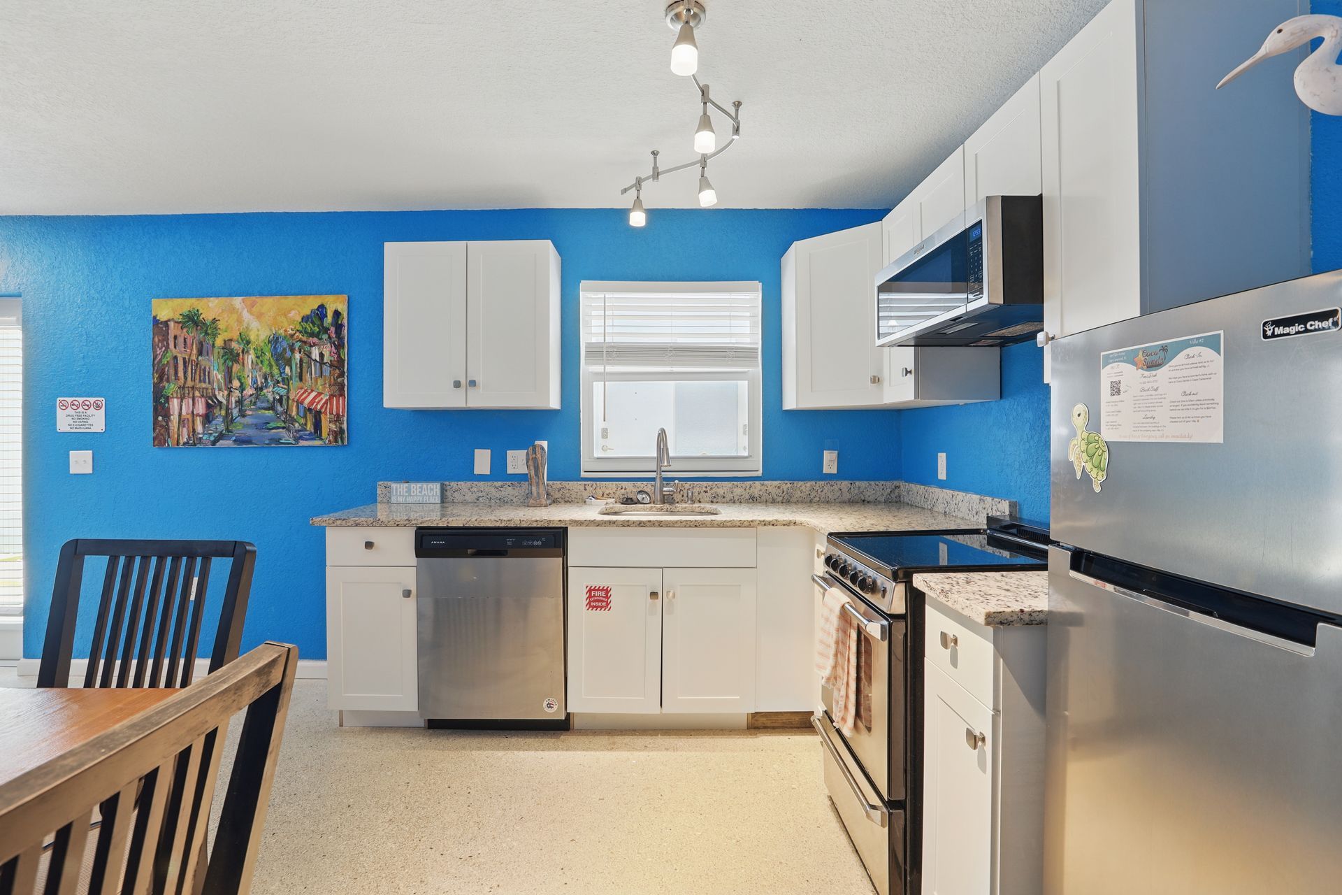 A kitchen with blue walls and white cabinets