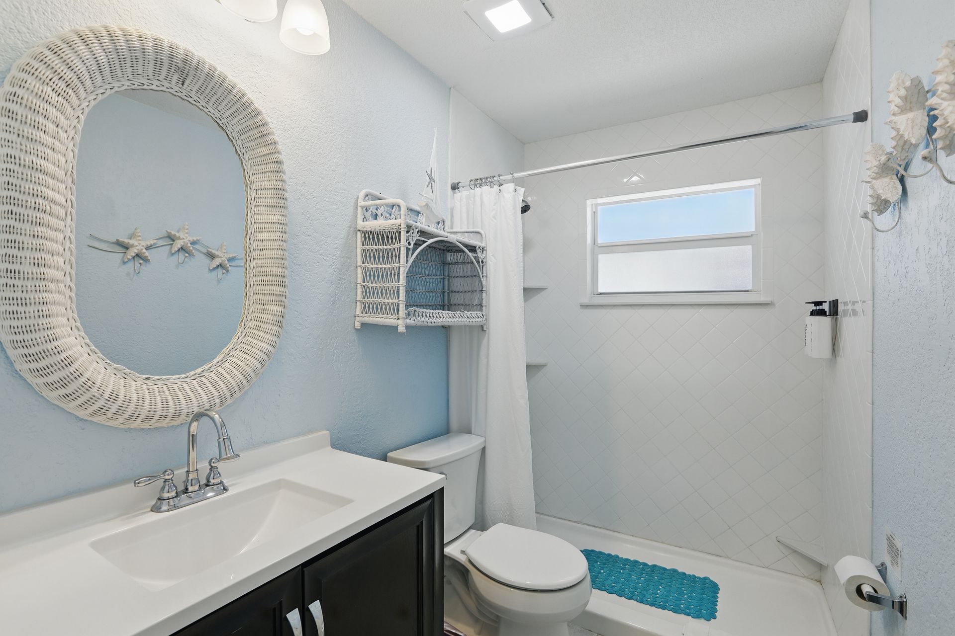 A bathroom with a toilet , sink , mirror and shower.