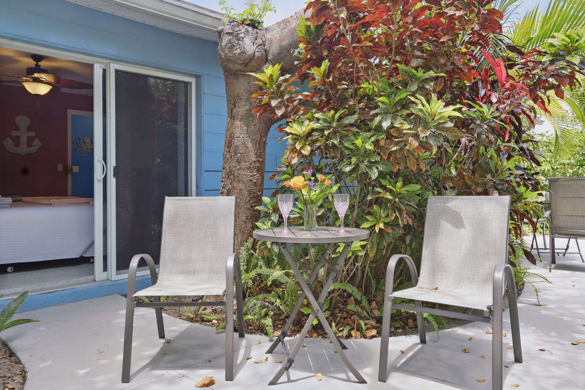 A patio with a table and chairs in front of a blue house.