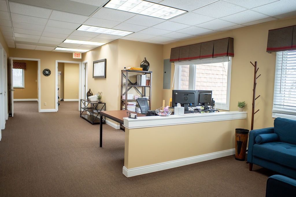 Office interior with reception desk, hallway, and waiting area with sofa.