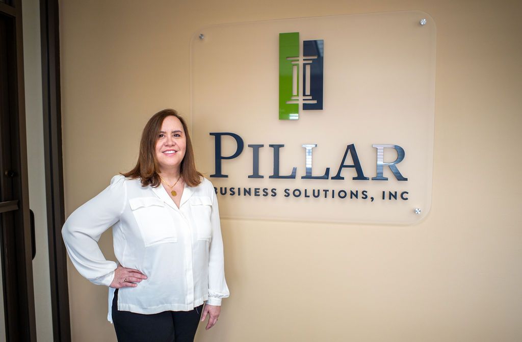 Woman stands by a company sign reading
