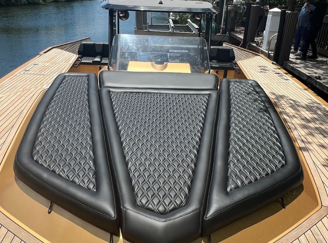 The back of a boat is sitting on a dock next to a body of water.