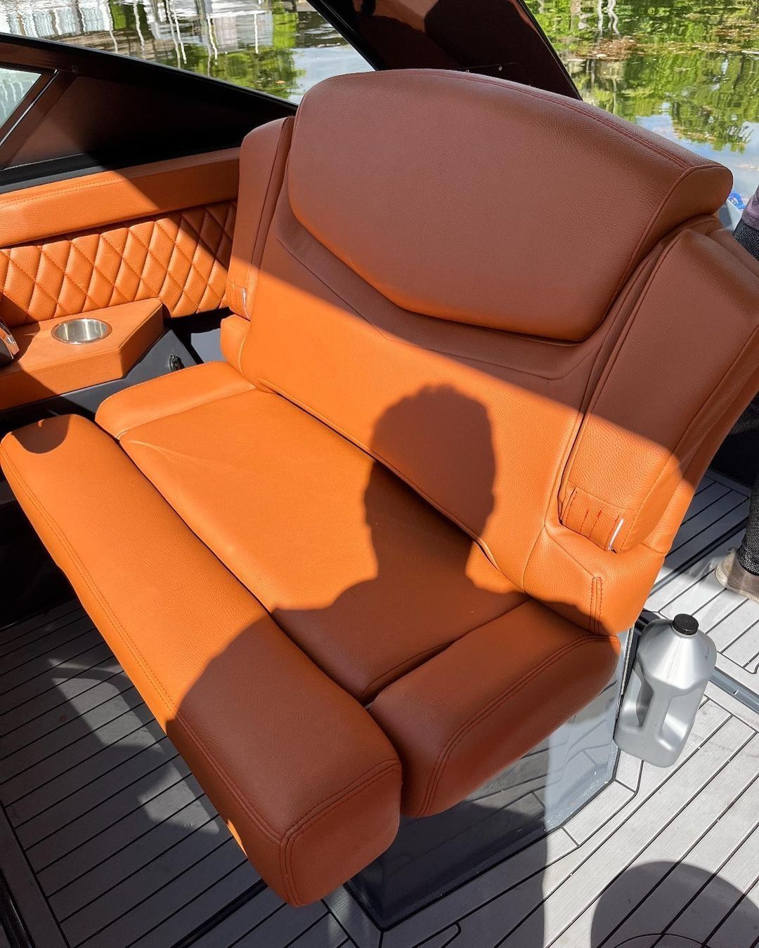 A brown leather seat on a boat with a cup holder