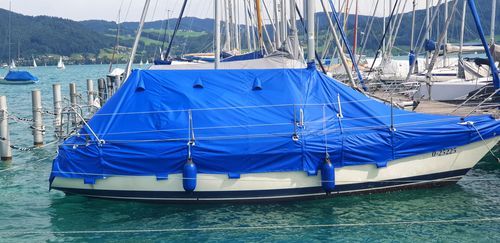 A boat is covered in a blue tarp in the water.
