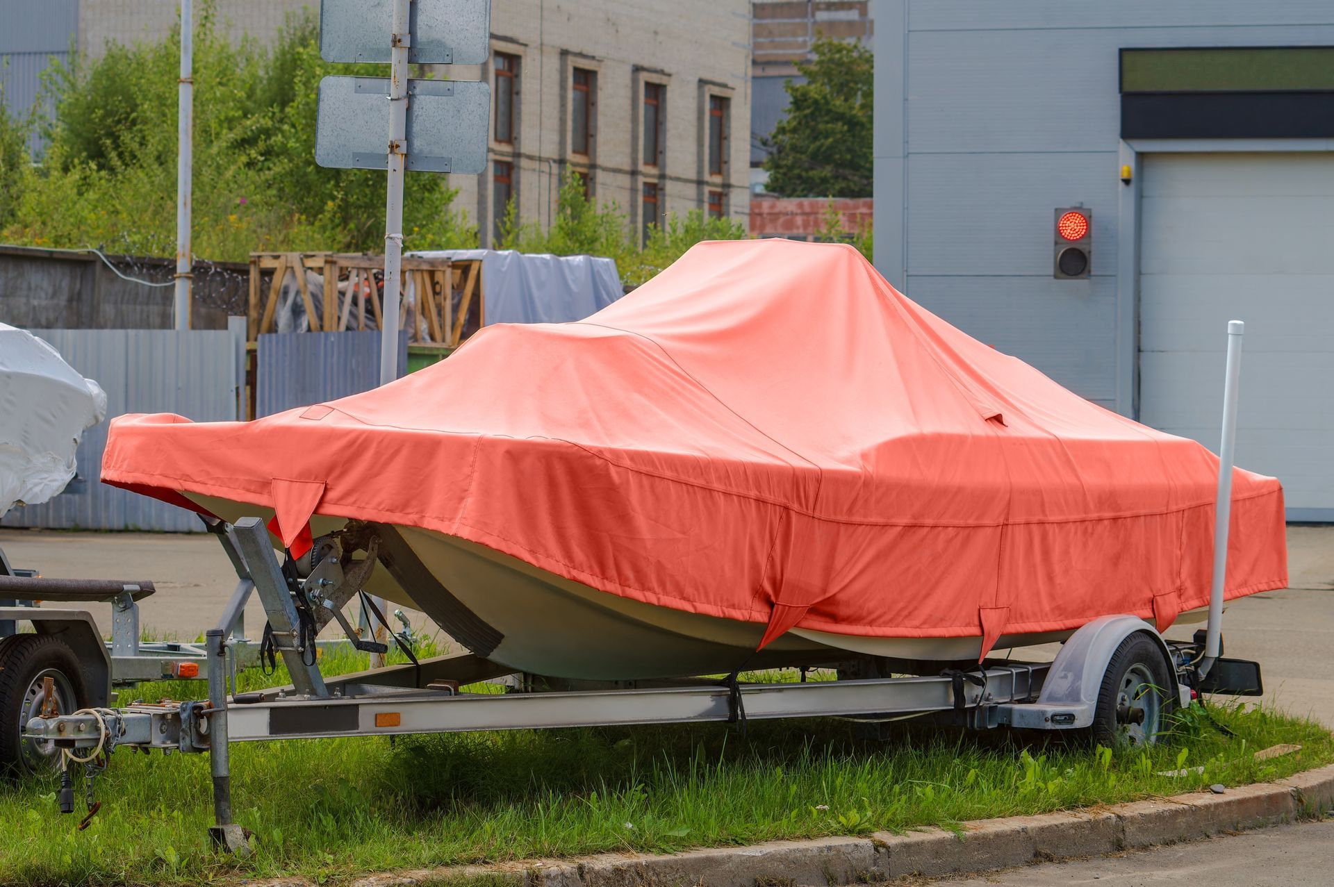 A boat is covered in an orange tarp on a trailer.