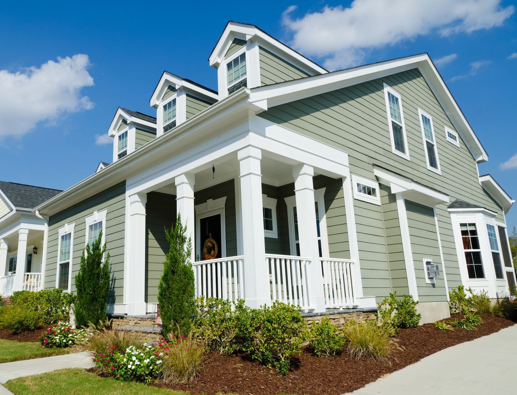 A green and white house with a large porch