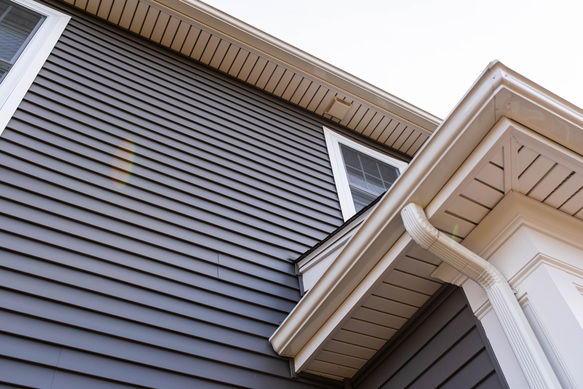 A house with a gray siding and a white gutter