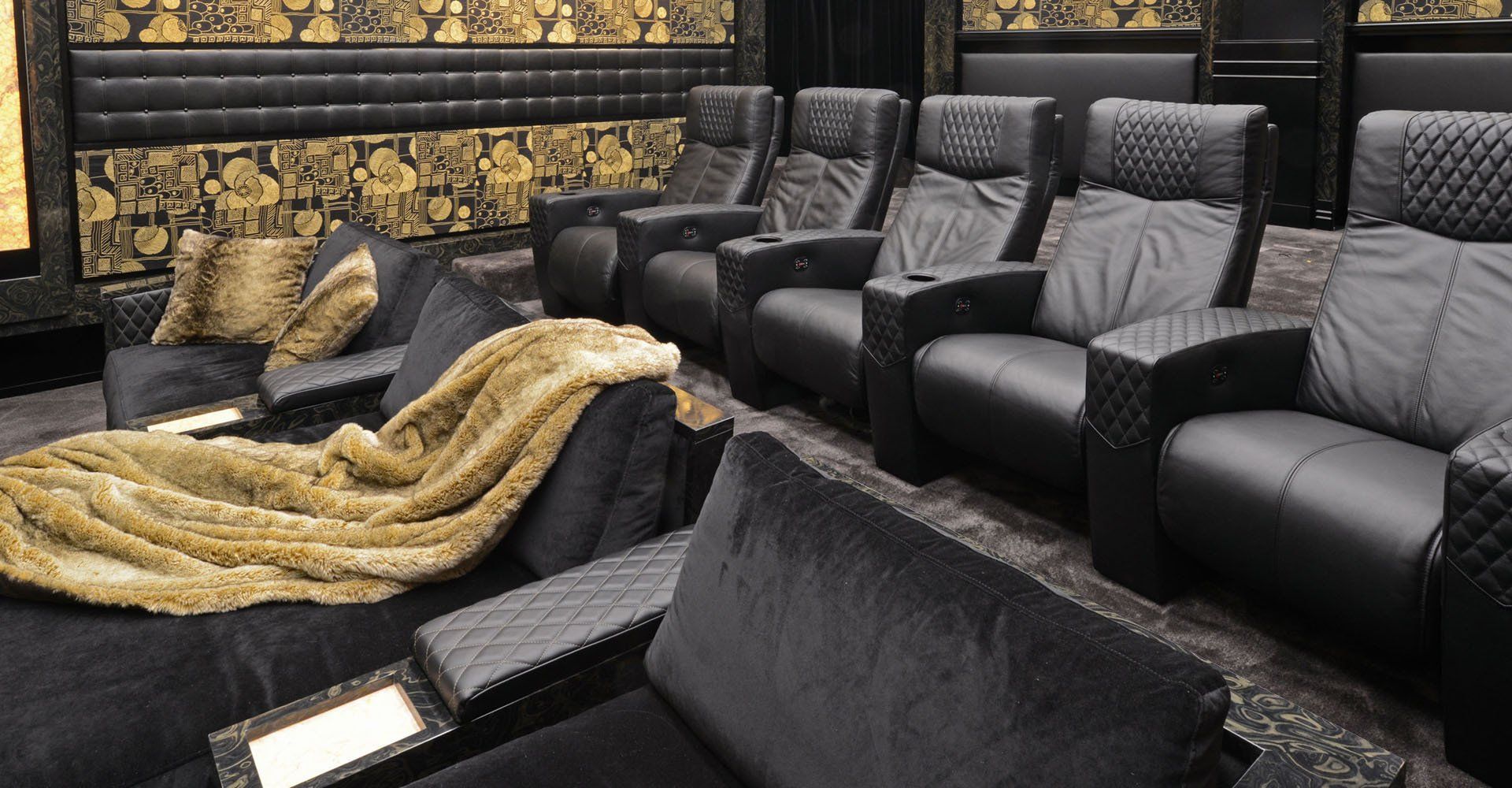 A row of black leather chairs in a theater with a blanket on the floor.