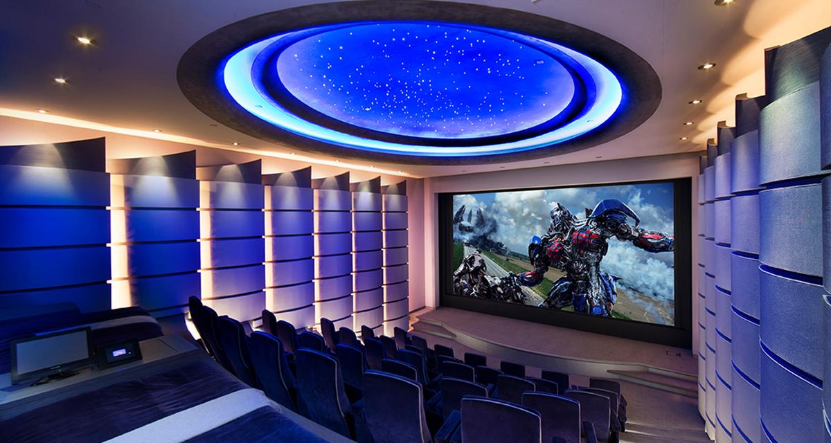 A home theater with a large screen and blue lights on the ceiling.
