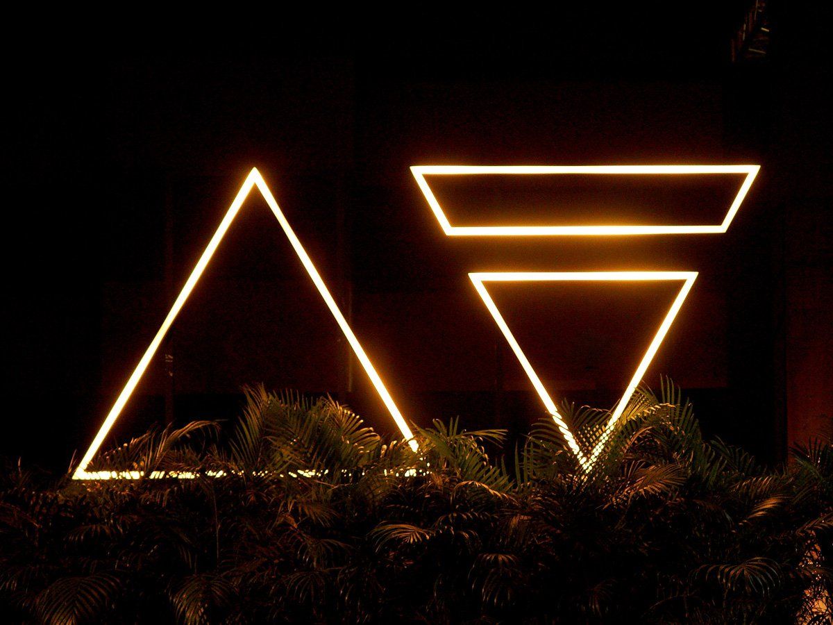 Two neon triangles are lit up in the dark.
