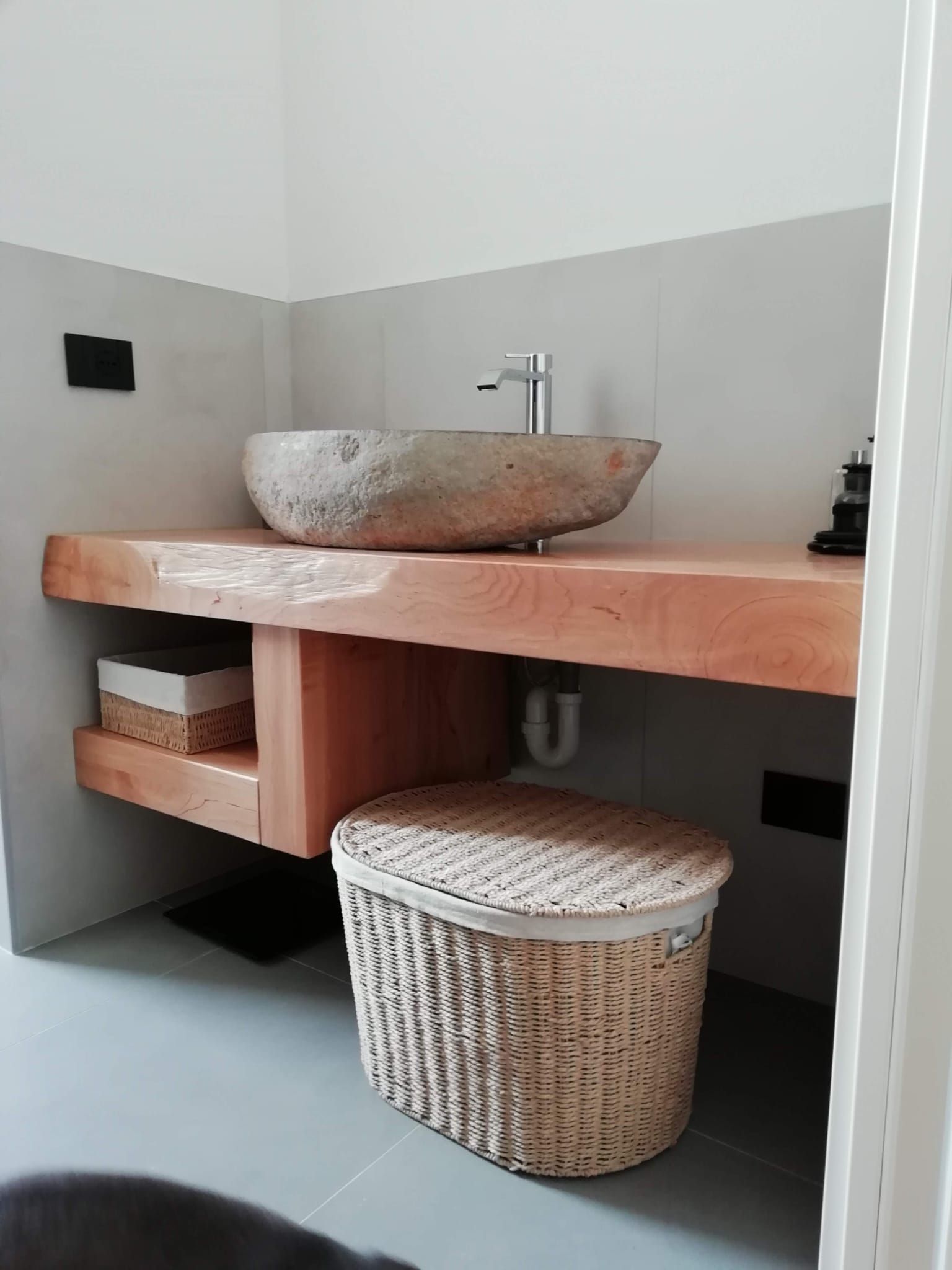 Un bagno con lavabo in pietra e cesto in vimini