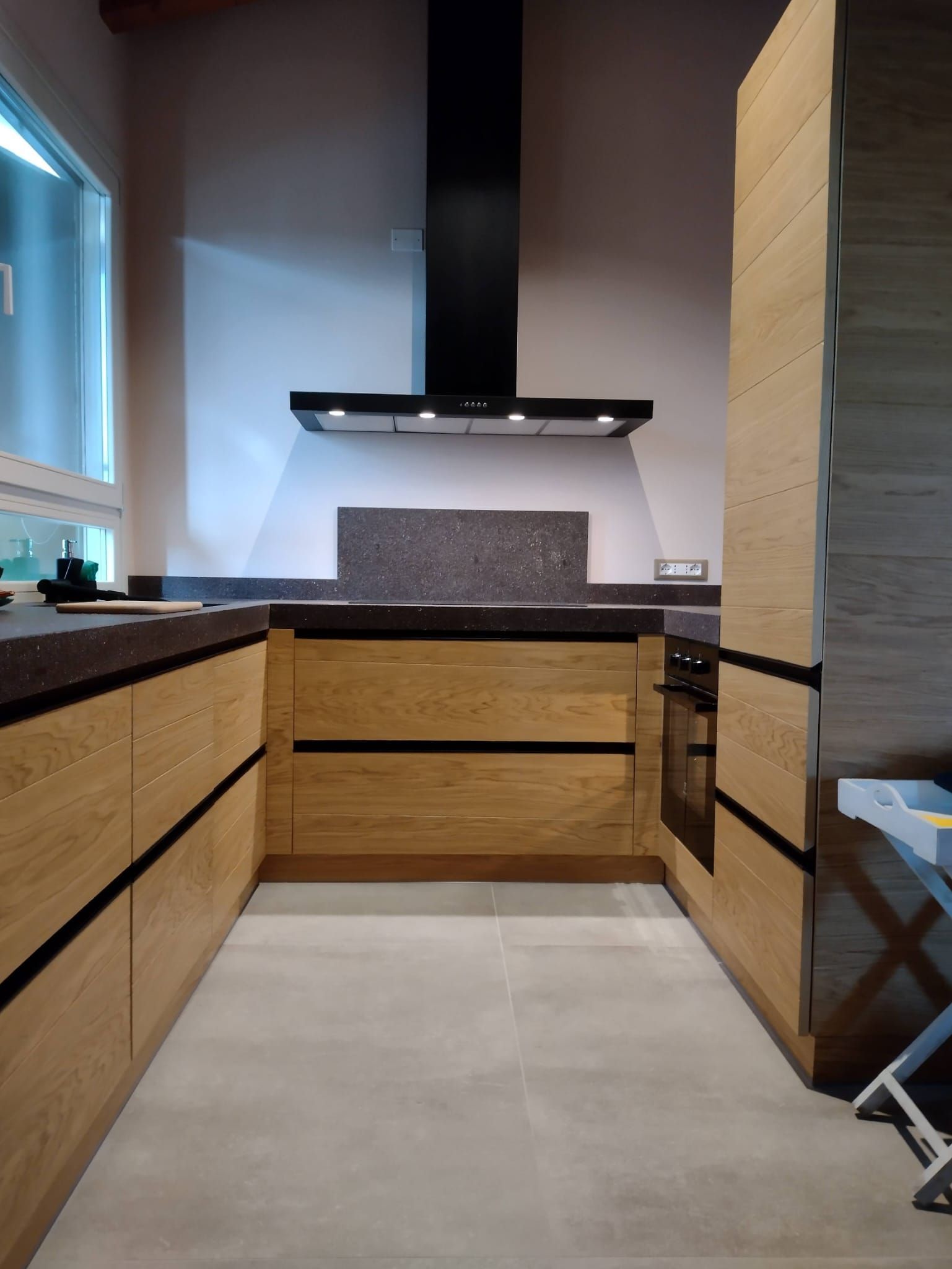 Una cucina con mobili in legno e cappa nera