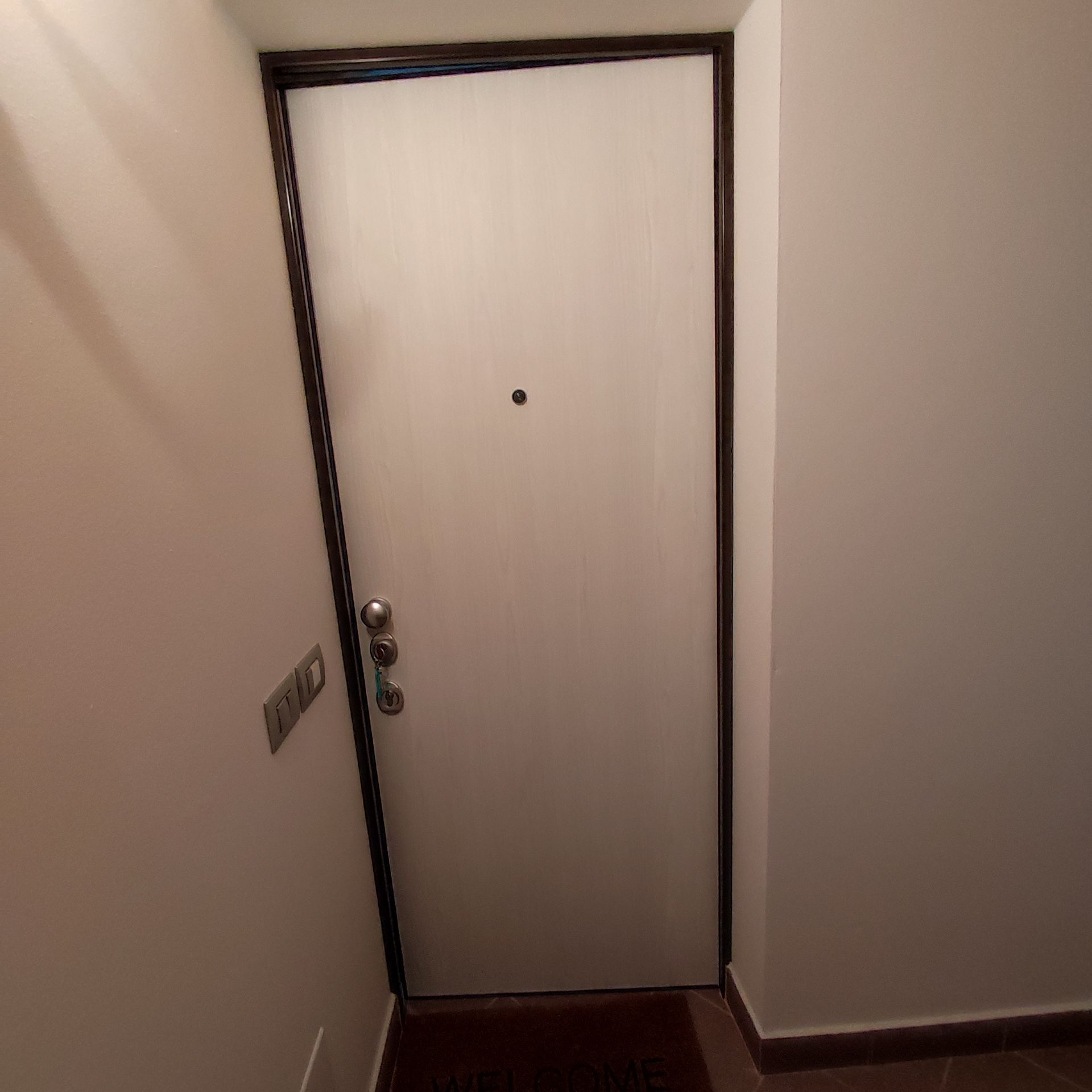 In un corridoio c'è una porta bianca con una cornice marrone