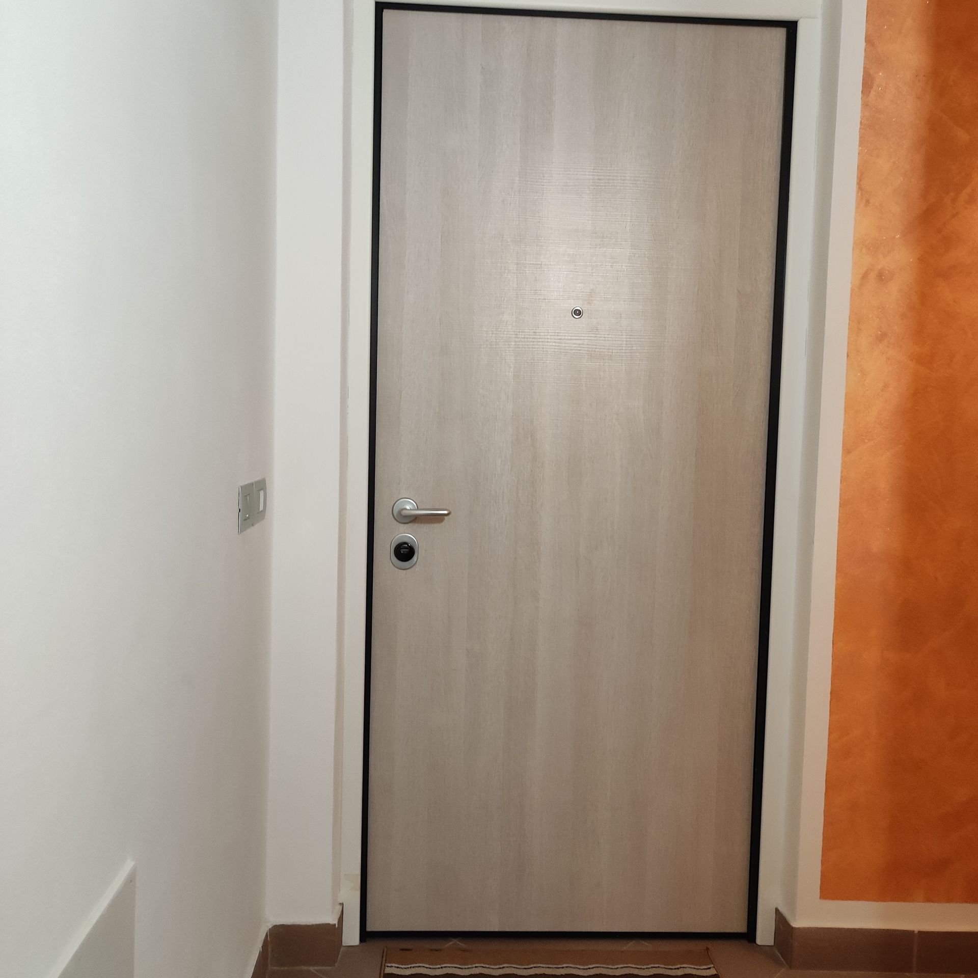 Una porta di legno si trova in un corridoio accanto a un muro.