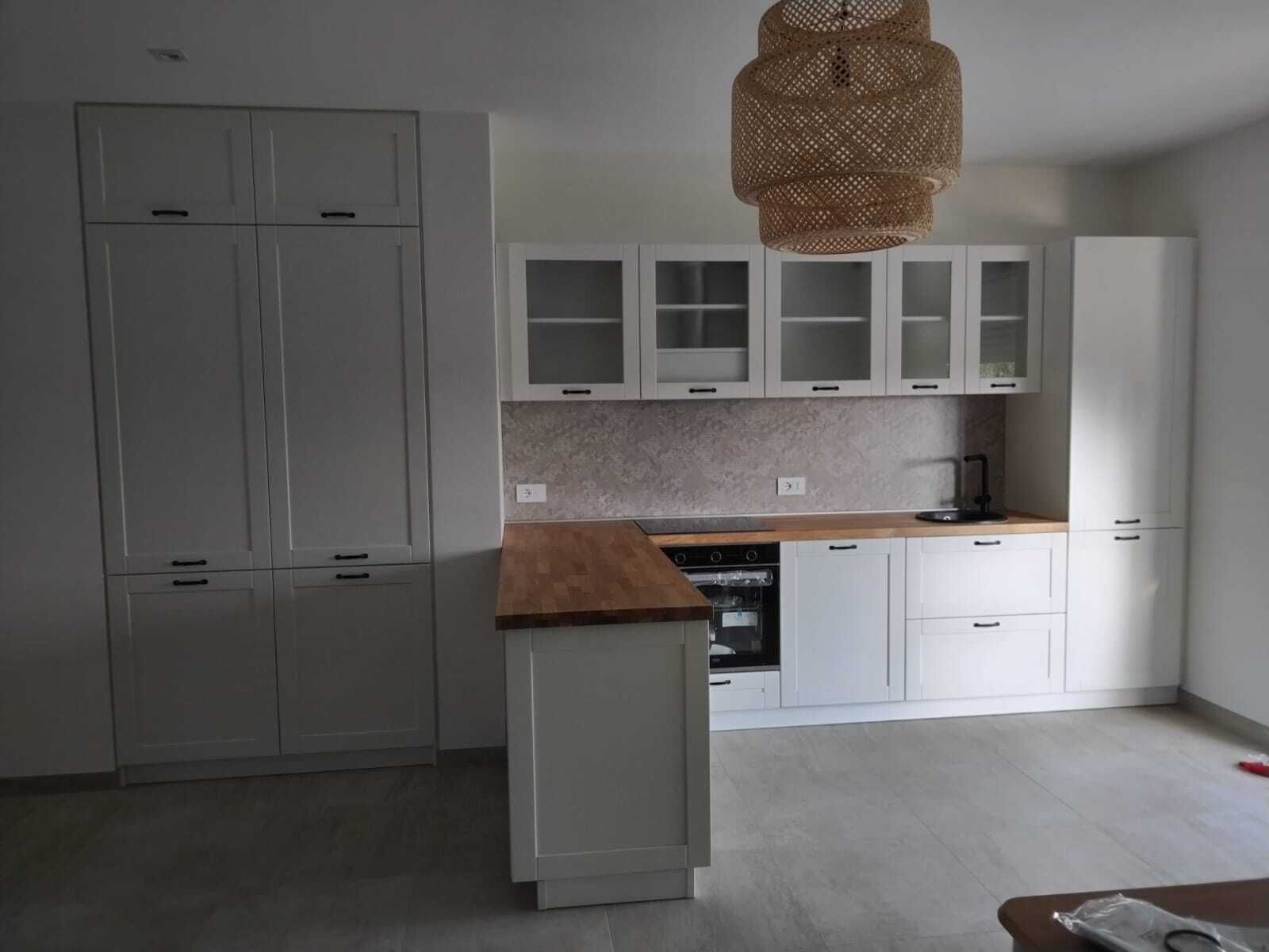 Una cucina con mobili bianchi e ripiano in legno