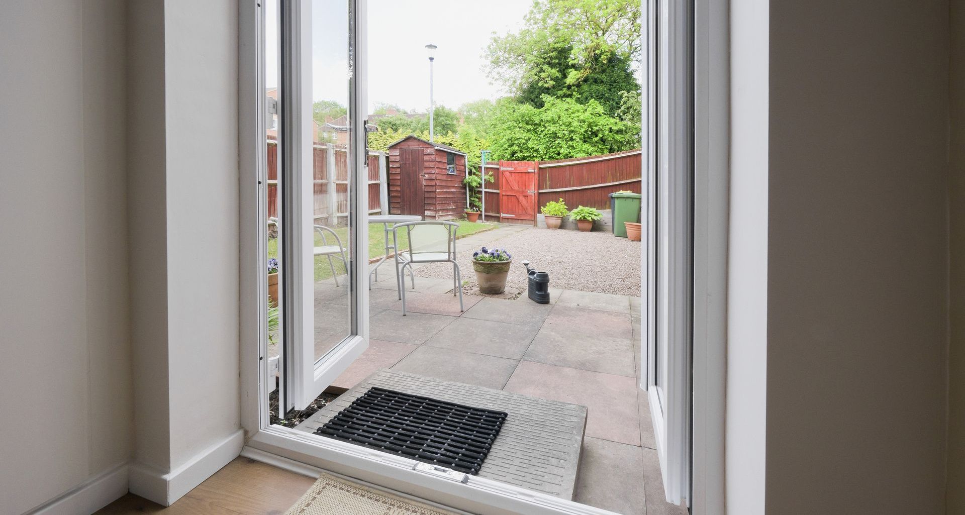 a doorway leading to a patio with a door mat on the floor .