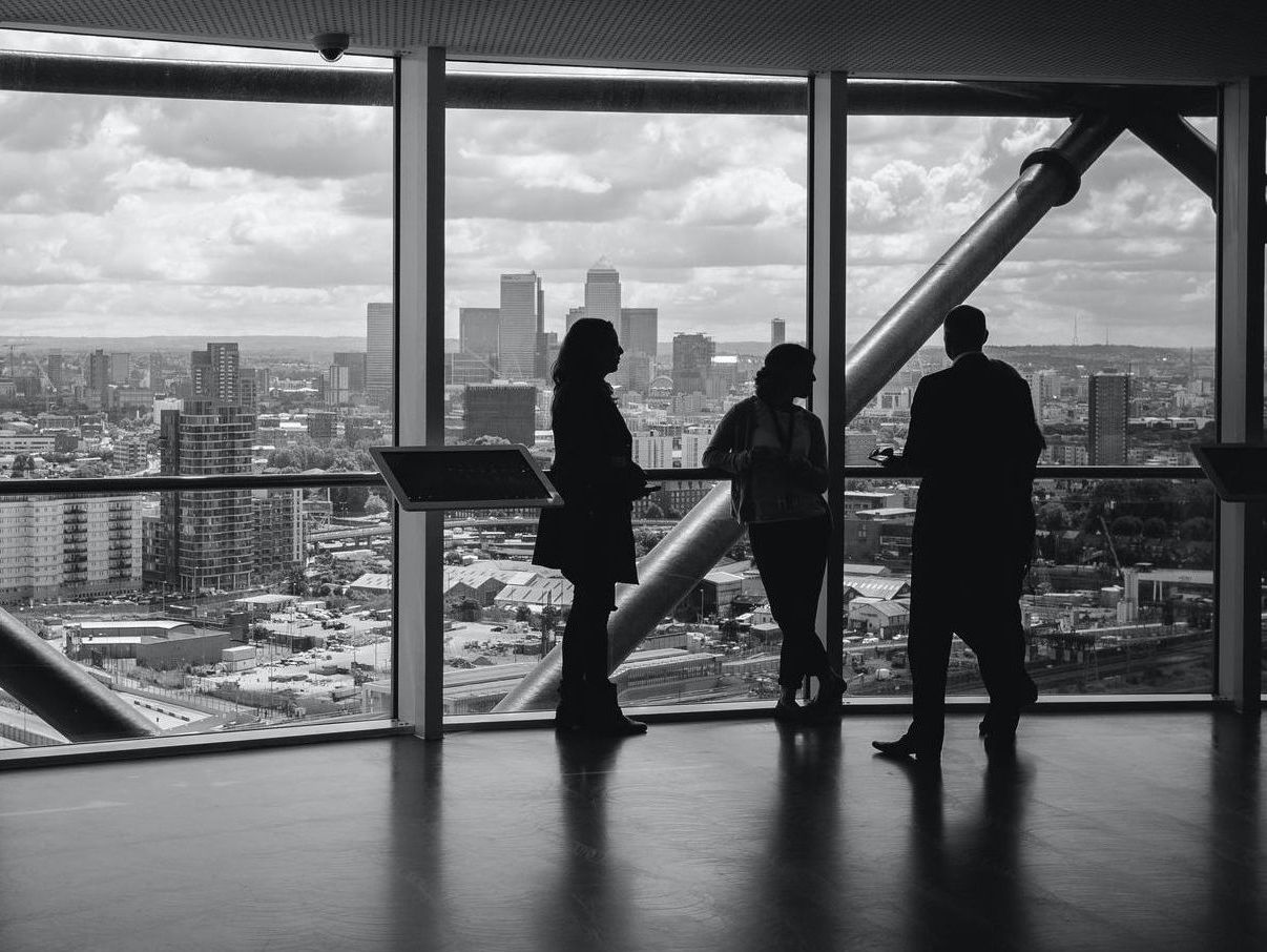 a group of people standing in front of a large window overlooking a city