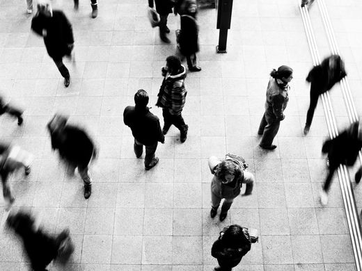 a black and white photo of people walking on a tiled floor
