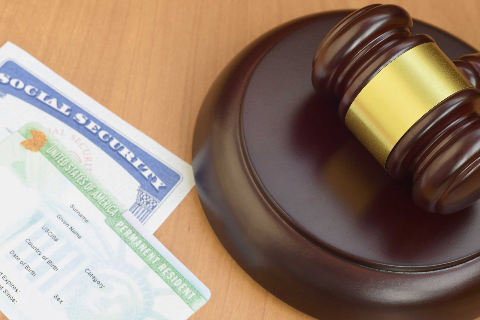 judge’s gavel beside a Social Security card and a U.S. resident card on a desk.