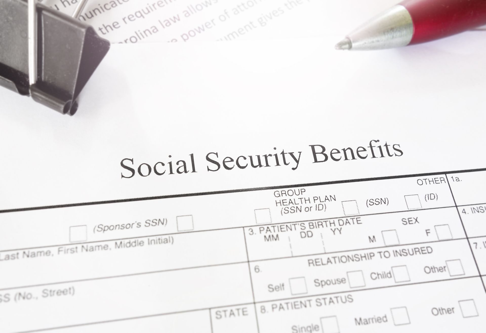 Form titled Social Security Benefits on a desk with a pen and binder clip ready for completion.