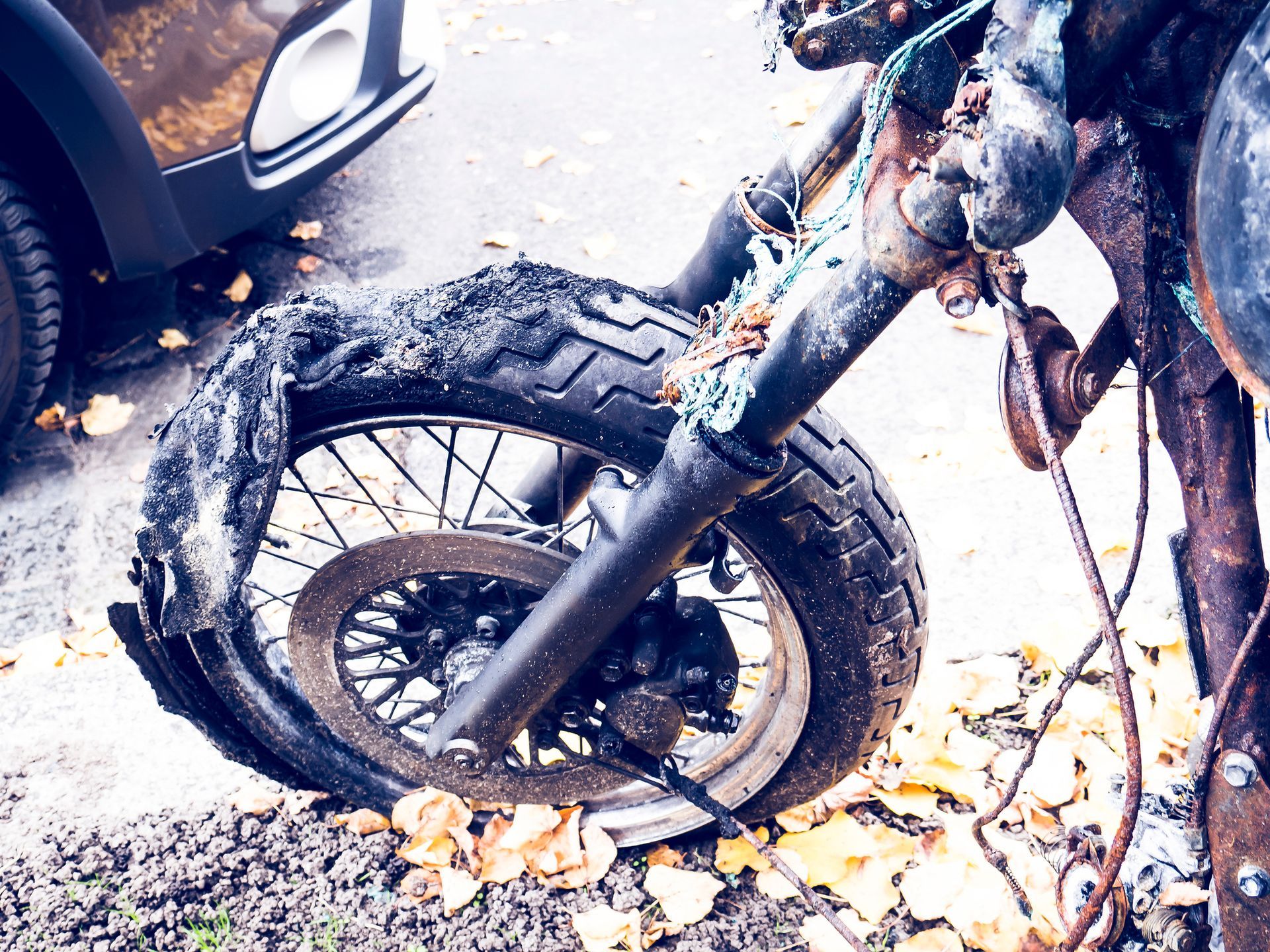 A motorcycle with a broken tire is parked on the side of the road.