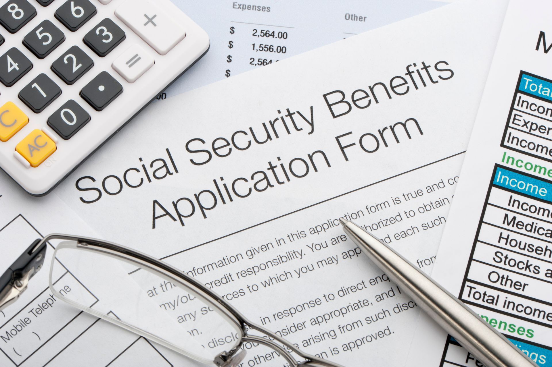 A close-up of a social security application with a calculator and pen