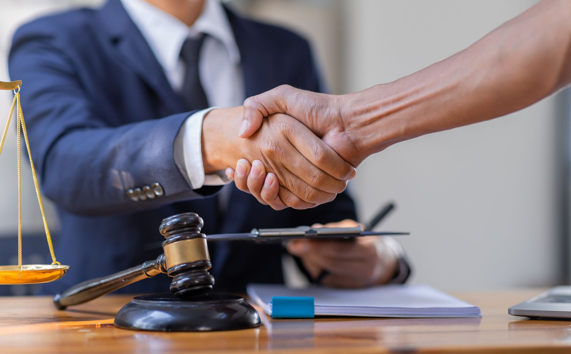 A social security attorney in a blue suit, shaking hands with an individual at an office.