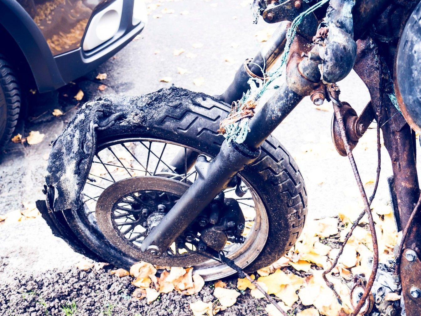 A motorcycle with a broken tire is parked on the side of the road.