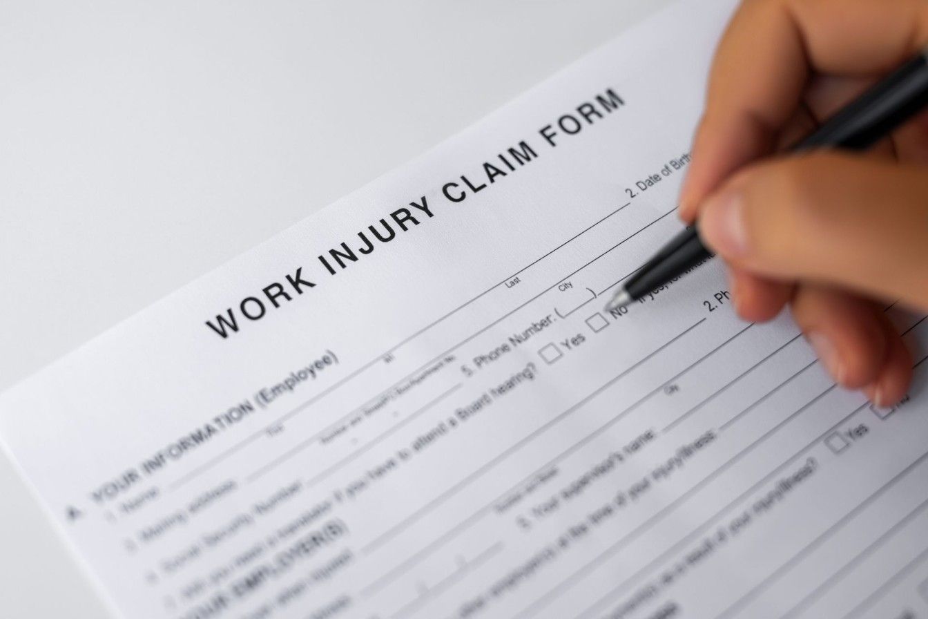 A person is filling out a work injury claim form