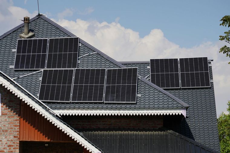 House roof covered with solar panels under a partly cloudy sky