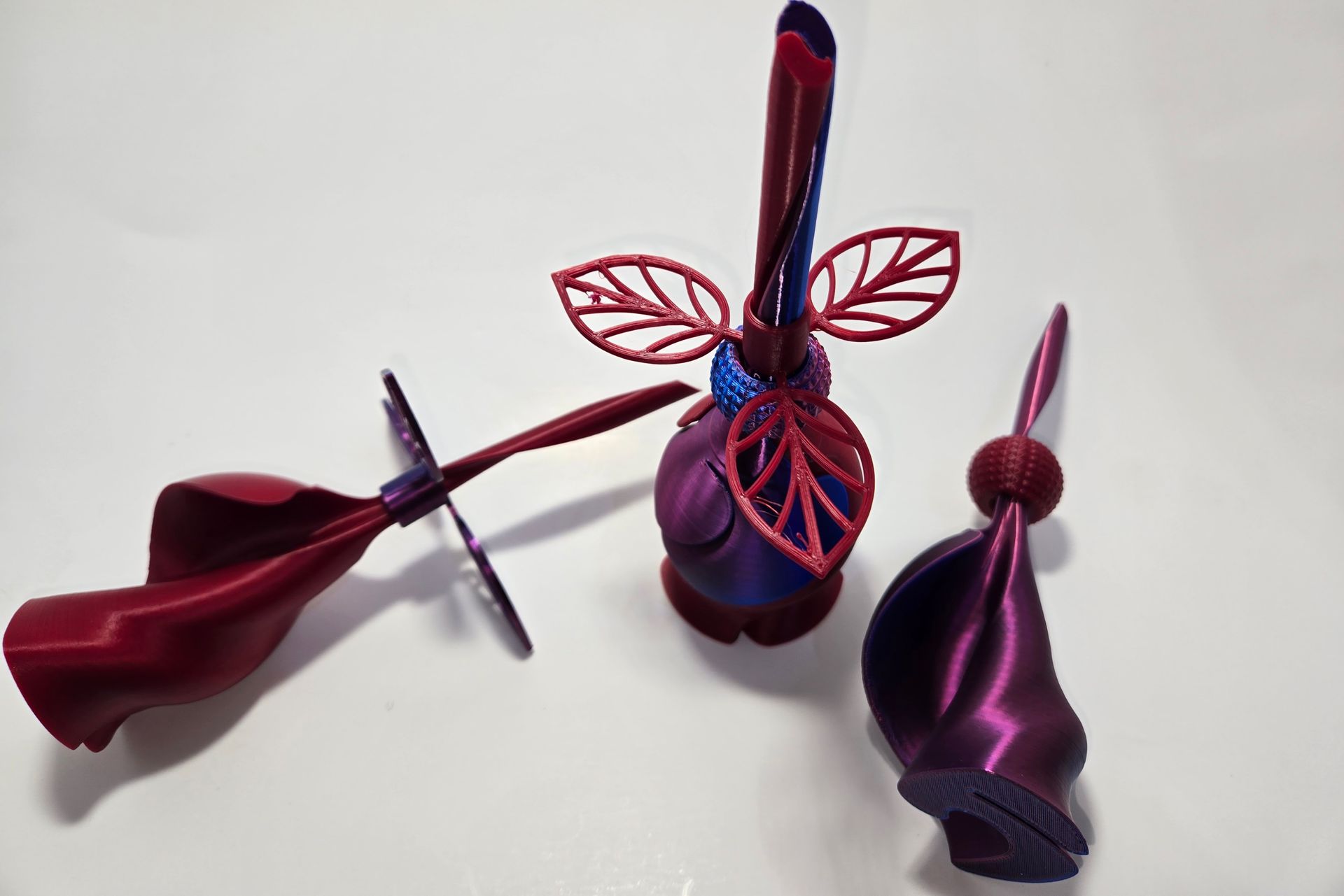 Two purple flowers with red leaves are sitting on a white surface.