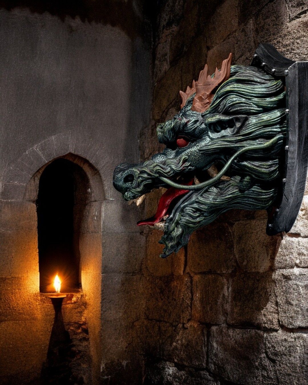 A statue of a dragon on a shield on a brick wall