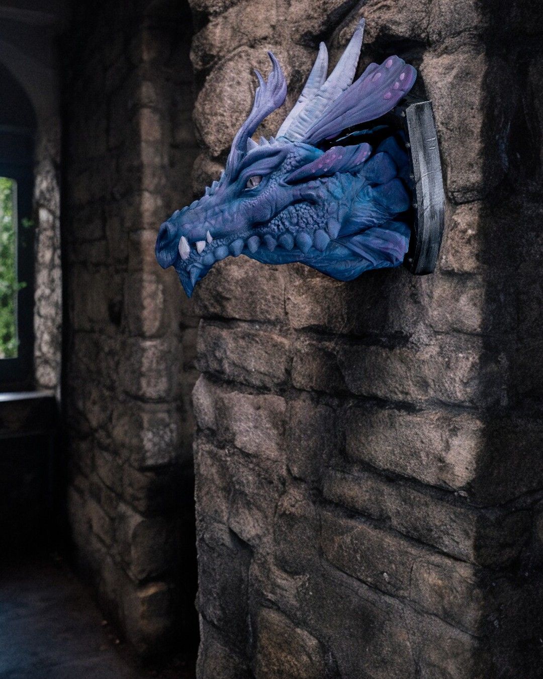 A blue and purple dragon head is hanging on a brick wall