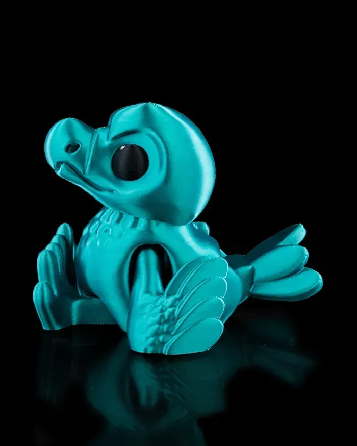 A turquoise figurine of a bird is sitting on a black surface