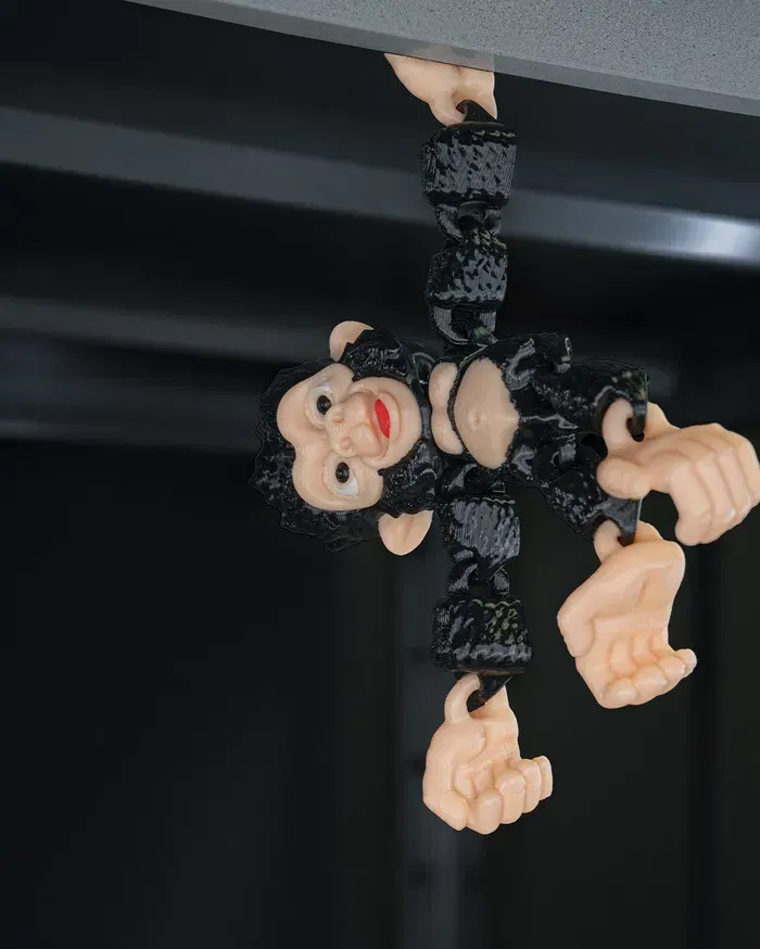 A toy gorilla with a bow tie is sitting on a black surface.