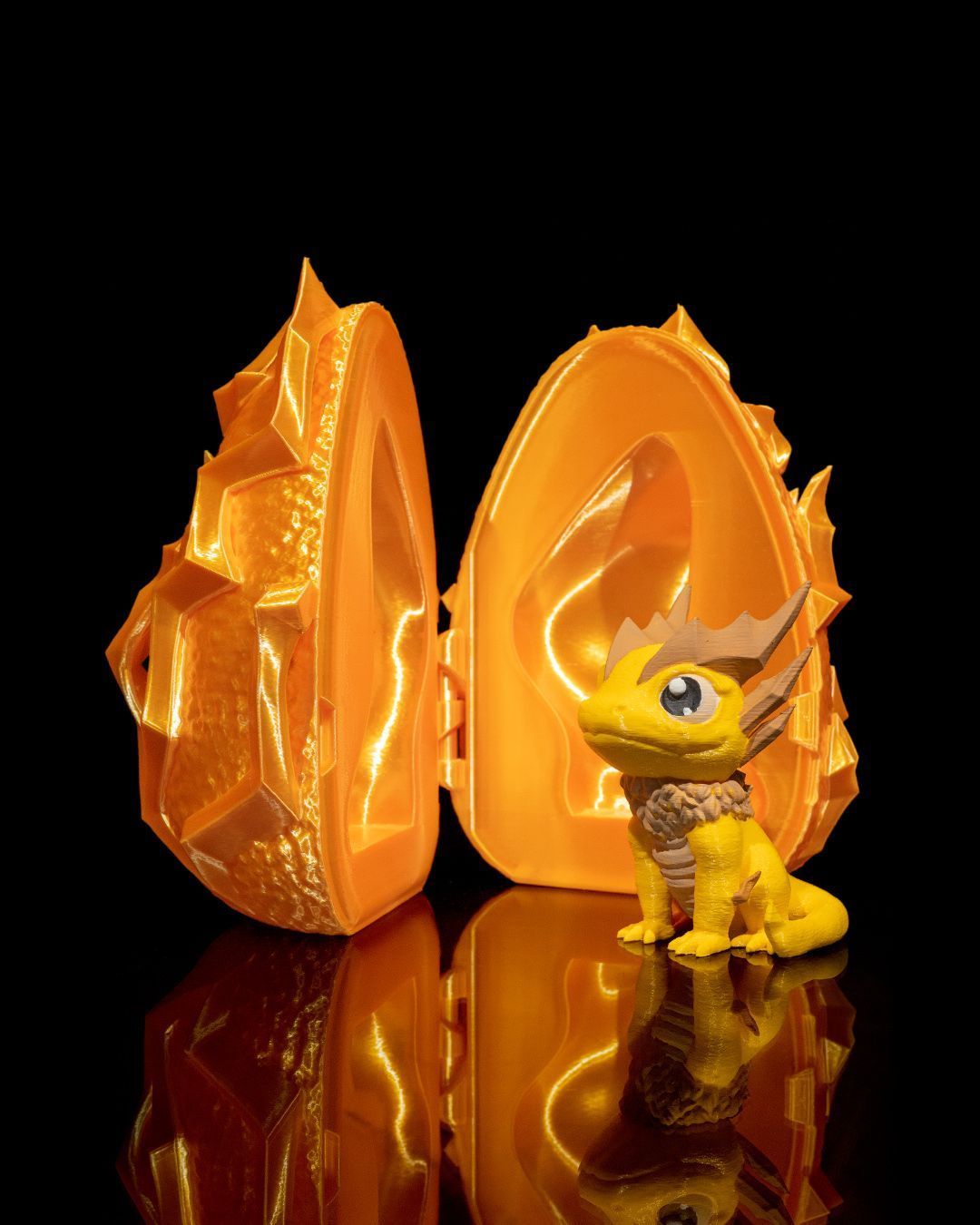 A yellow toy dragon is sitting next to an orange egg.