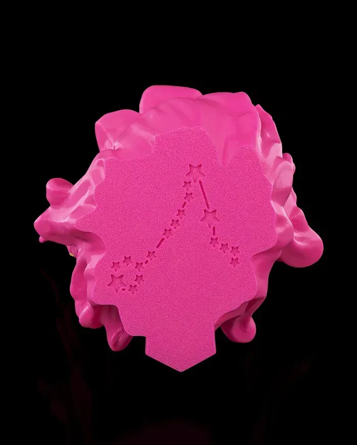 A pink statue of two fish with a yellow tail on a black background.