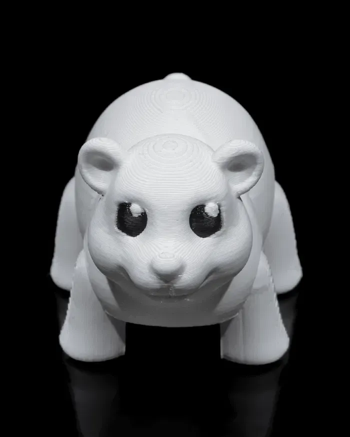 A white toy polar bear is sitting on a black surface.