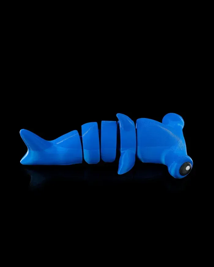A blue hammerhead shark toy is laying on a black surface.