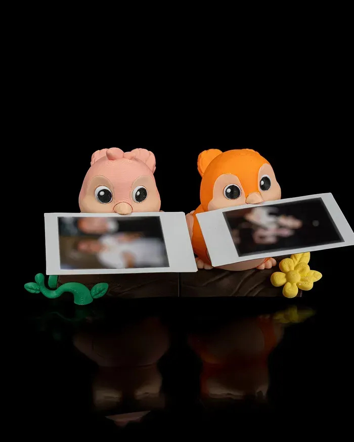 Two birds , one pink and one orange , are sitting on a tree branch.