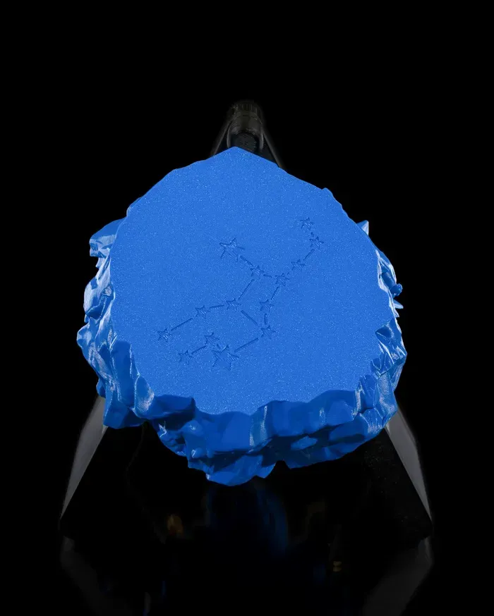 A blue statue of a woman sitting on a rock with the letter m on it.