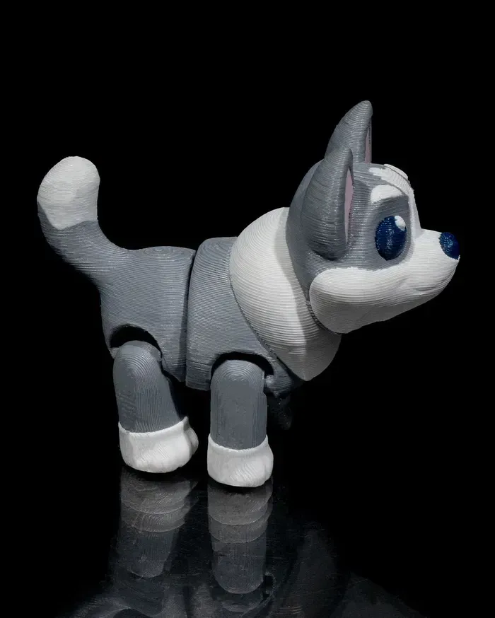 A gray and white husky dog toy is standing on a black surface.
