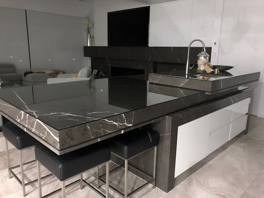 A Kitchen With A Black Marble Countertop And Stools — United Kitchens and Joinery in Wollongong, NSW